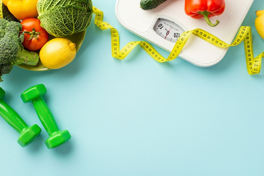 Bathroom scale, tape measure, dumbbells and fresh vegetables